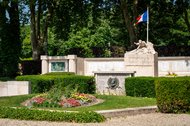 Bild des Kriegerdenkmals in der Ville de Péronne, der französischen Partnerstadt Altenas. Die französische Fahne weht über einer Statue auf einem Sockel, der vor einer breiten Wand aus Marmor mit vielen Namen steht.
