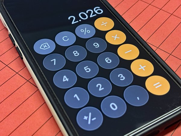 Symbolbild eines Smartphones mit geöffneter Taschenrechner-App, auf einer Laufmappe liegend.