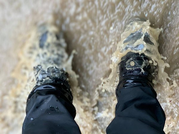 Stiefel im strömenden Wasser bei einer Flut, von oben aufgenommen.