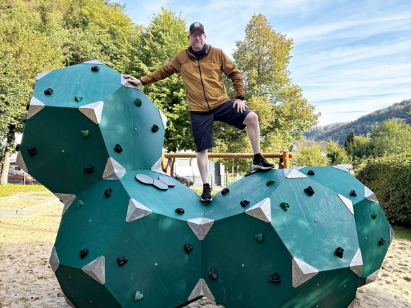 Gerrit Standke steht auf dem neuen Klettergerät, das aus Fünfeck-Würfeln besteht und grün ist.