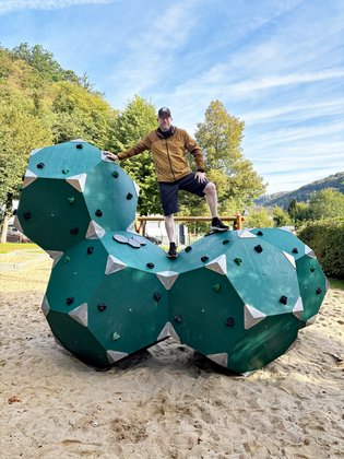 Gerrit Standke steht auf dem neuen Klettergerät, das aus Fünfeck-Würfeln besteht und grün ist.
